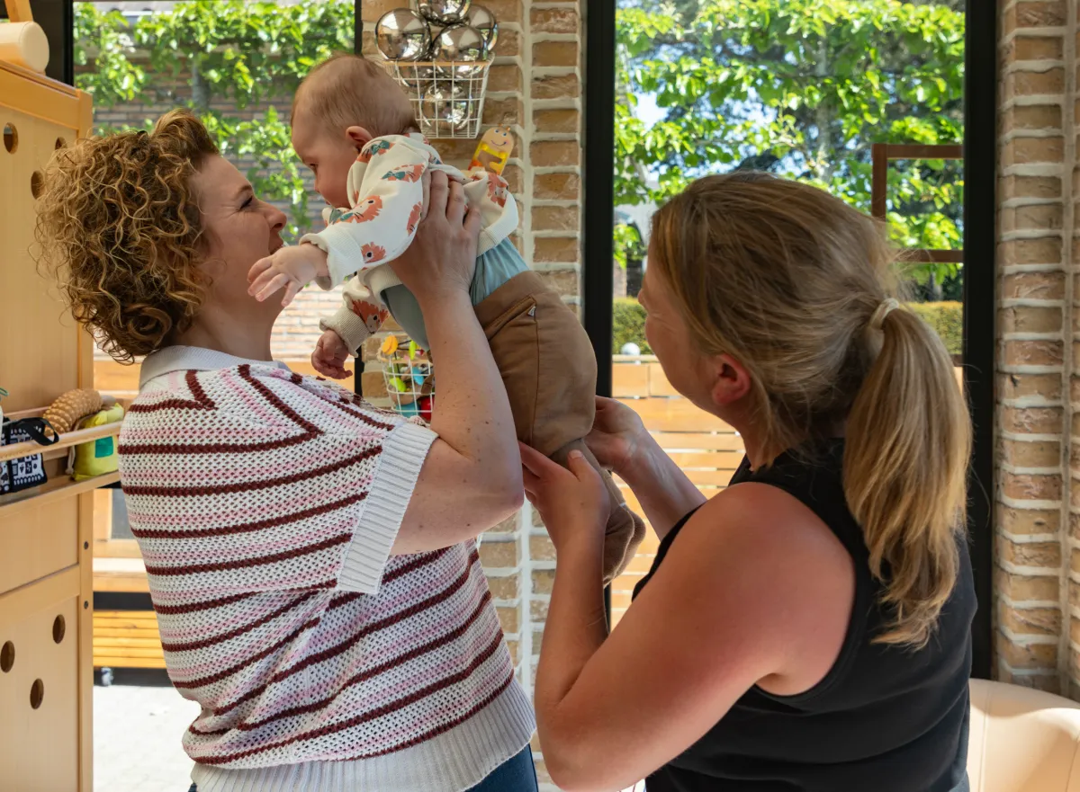 Photo of two childcare workers with a child.