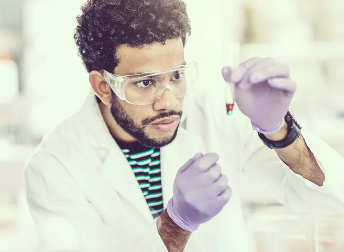 Jonge chemicus gaat oplettend te werk met zijn proefbuis en pipet