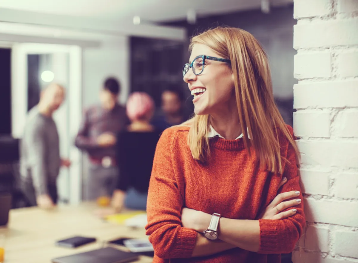 Jonge projectmanager kijkt lachend naar haar collega's