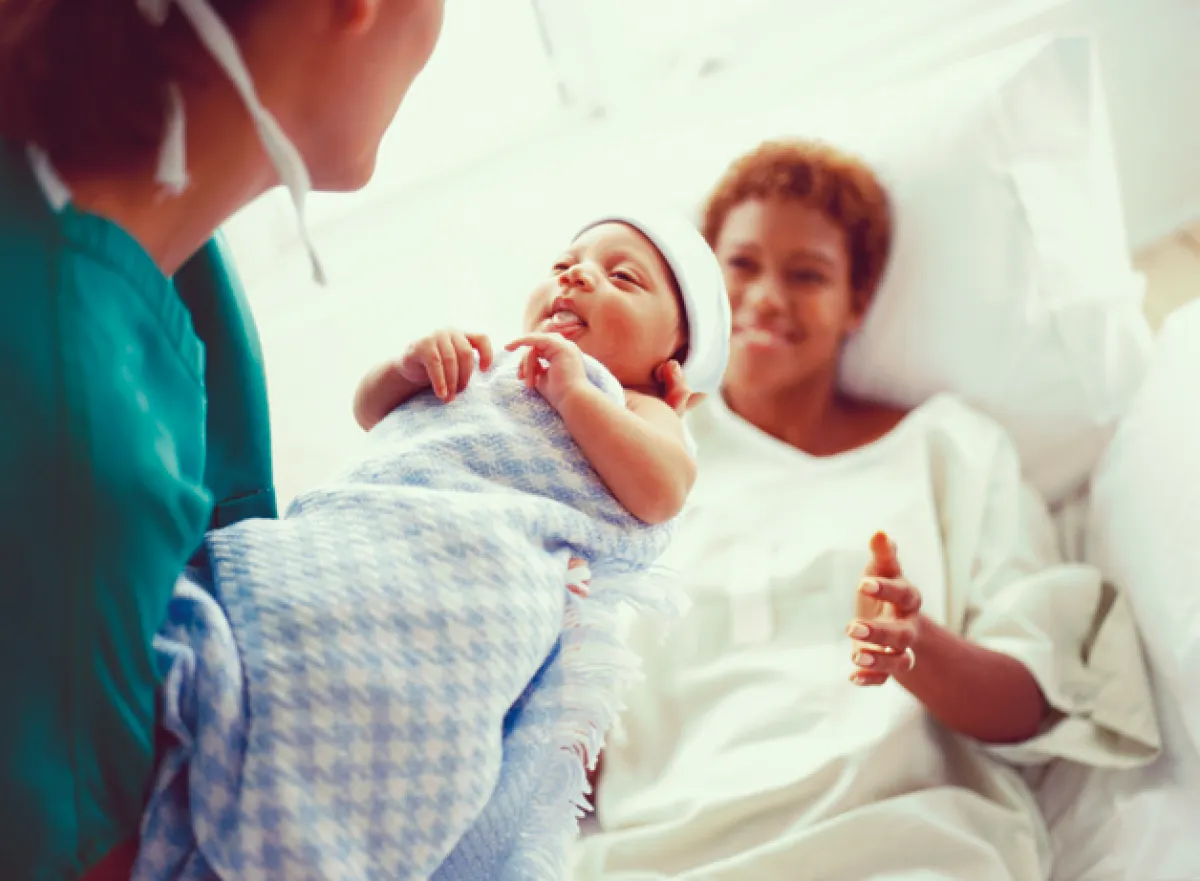 Een vroedvrouw heeft net een baby ter wereld geholpen en laat hem zien aan de moeder